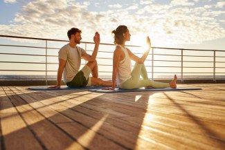 young couple doing yoga during sunrise on board of a cruiseship