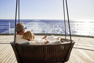 couple sitting in big swing on the spa deck of a cruiseship